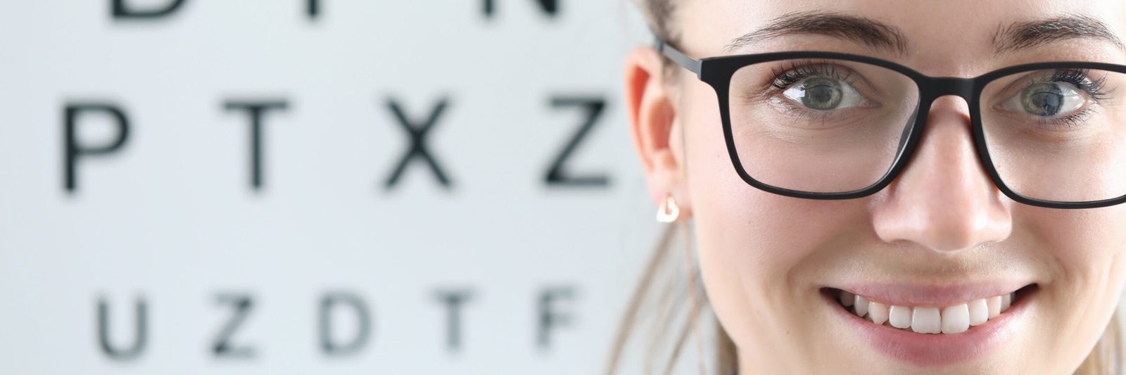 Smiling woman in glasses in front of an eye chart